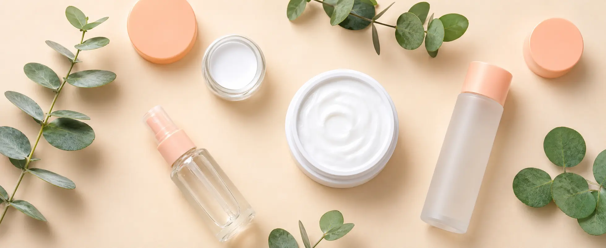 Minimalist skincare products and moisturizer with eucalyptus leaves on a beige background